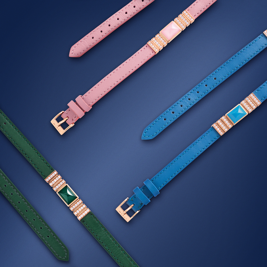 Green, pink and blue leather bracelets laying flat in a geometric pattern on a navy background