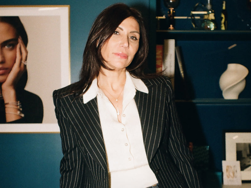 Woman in a pinstripe suit standing in an office setting with framed pictures on the wall.