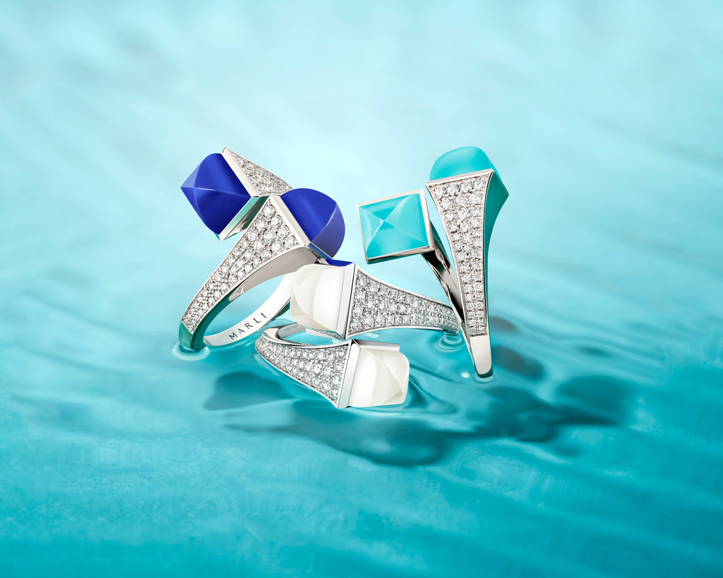 Three silver rings with blue and turquoise gemstones on a teal background