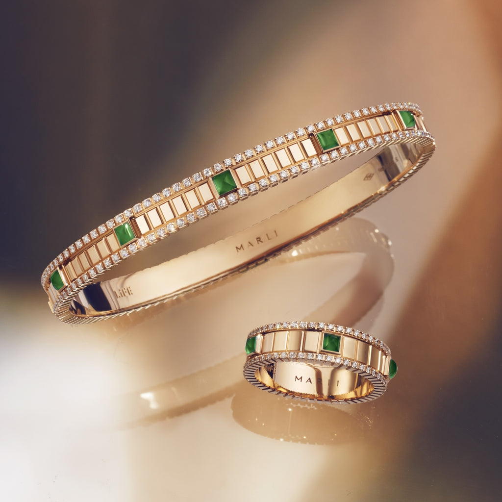 A rose gold bracelet and ring with green agate stones an diamonds. They sit on top of a blurred brown background