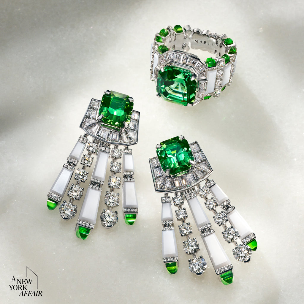 Pair of emerald and diamond earrings on a light gray background