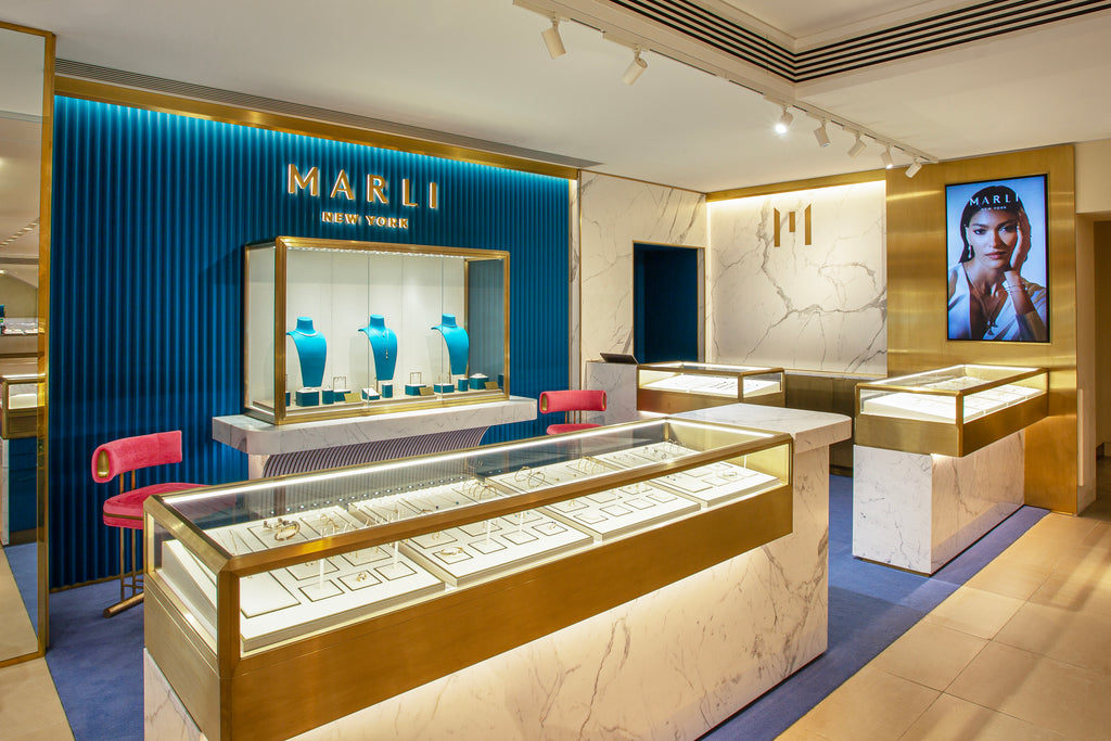 Interior shot of a jewelry boutique with gold and marble display cases in front of a teal focal wall.