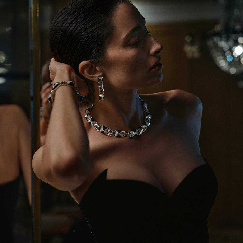 Woman adjusting her earrings in a dimly lit room