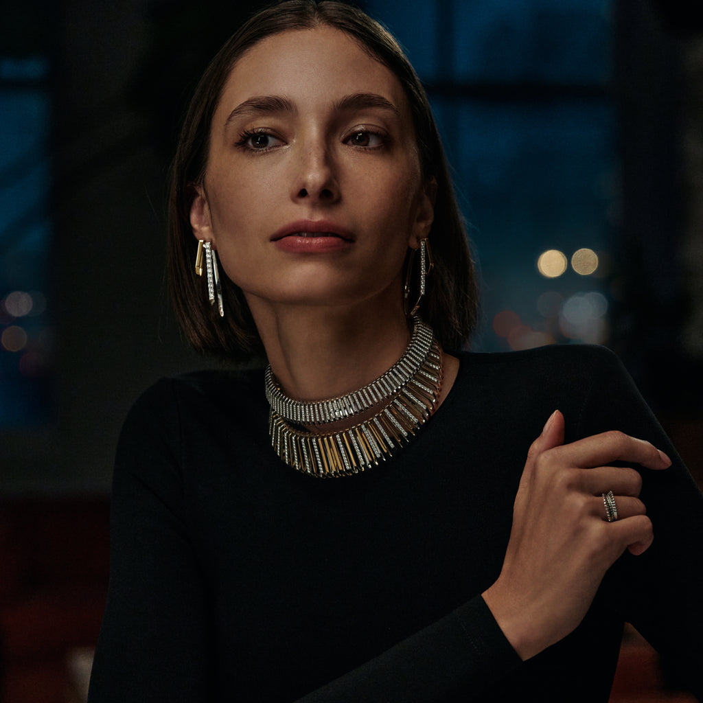 Woman wearing a black top and silver necklace with blurred lights in the background