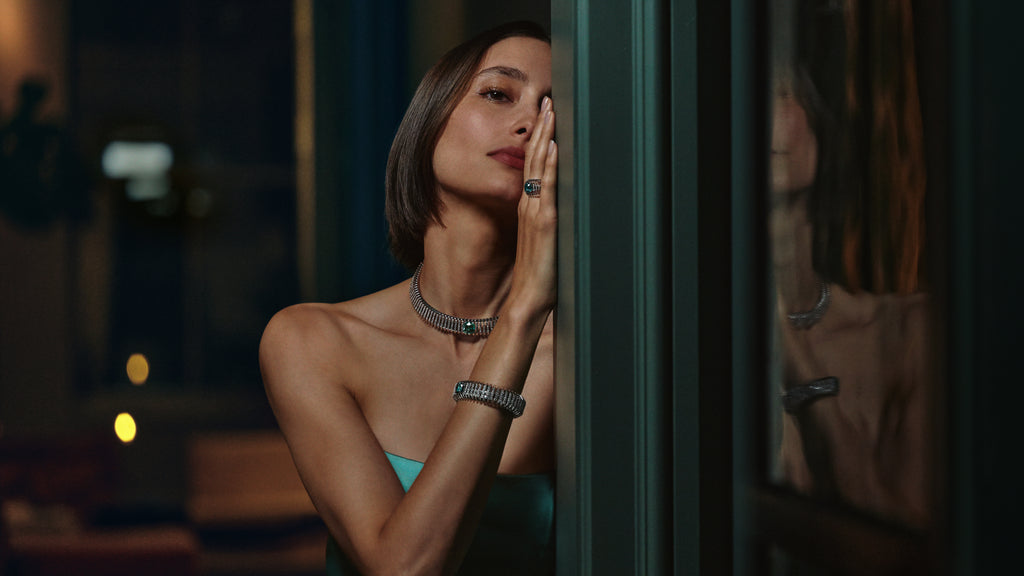 Woman in a green dress with jewelry in a dimly lit room