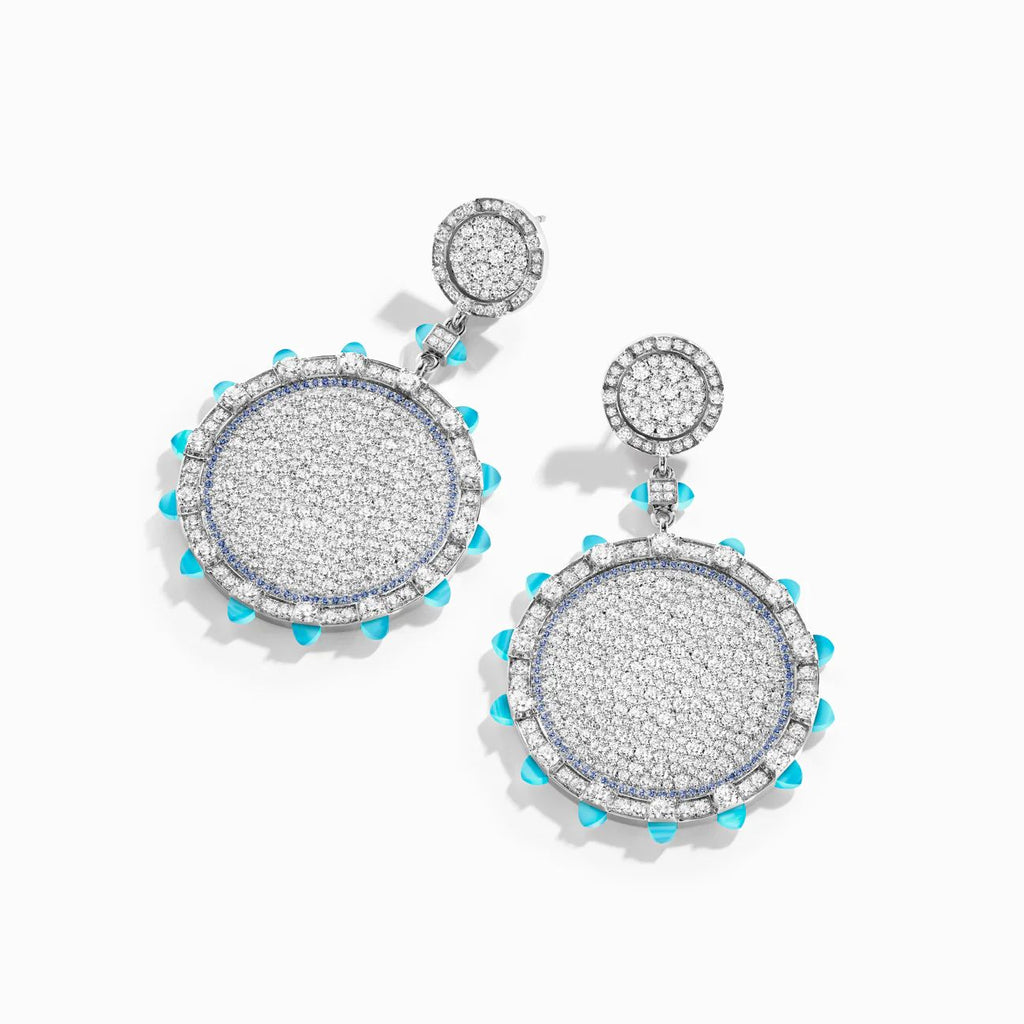 Pair of silver earrings with circular designs and turquoise accents on a white background
