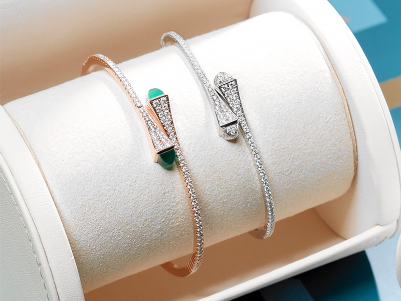 Two diamond bracelets shown in a cream jewelry display holder. 