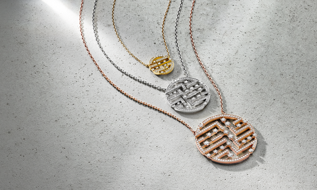 Three diamond necklaces in various sizes in rose gold, yellow gold and white gold, laying flat on cement