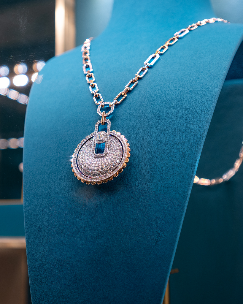 A diamond necklace on a teal display bust